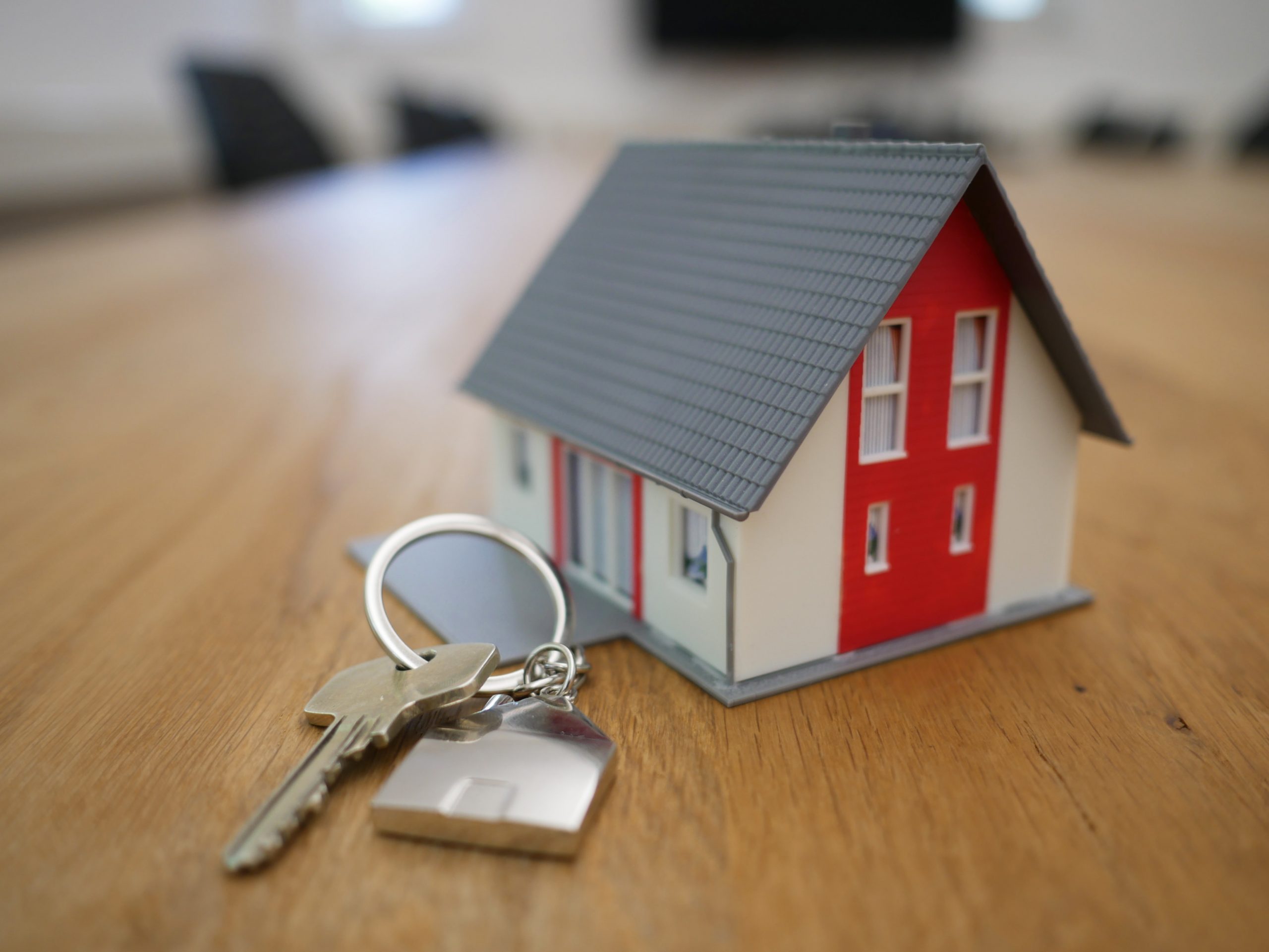 A house model painted gray, white, and red with a key next to it.